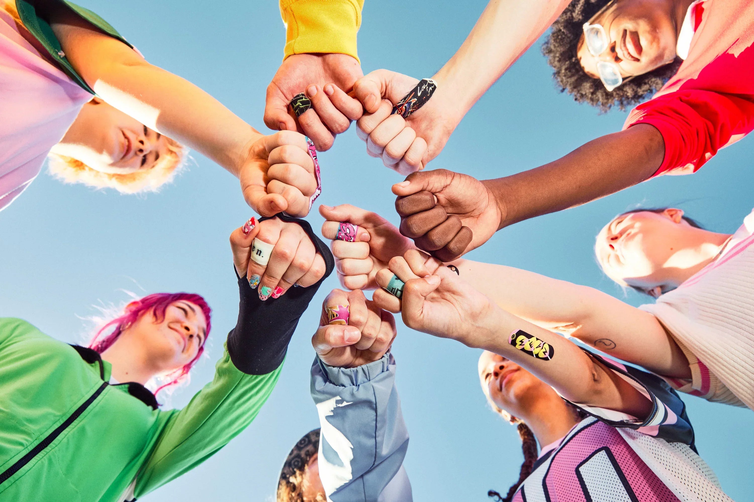 Teens stacking hands together wearing decorative bandages on their fingers