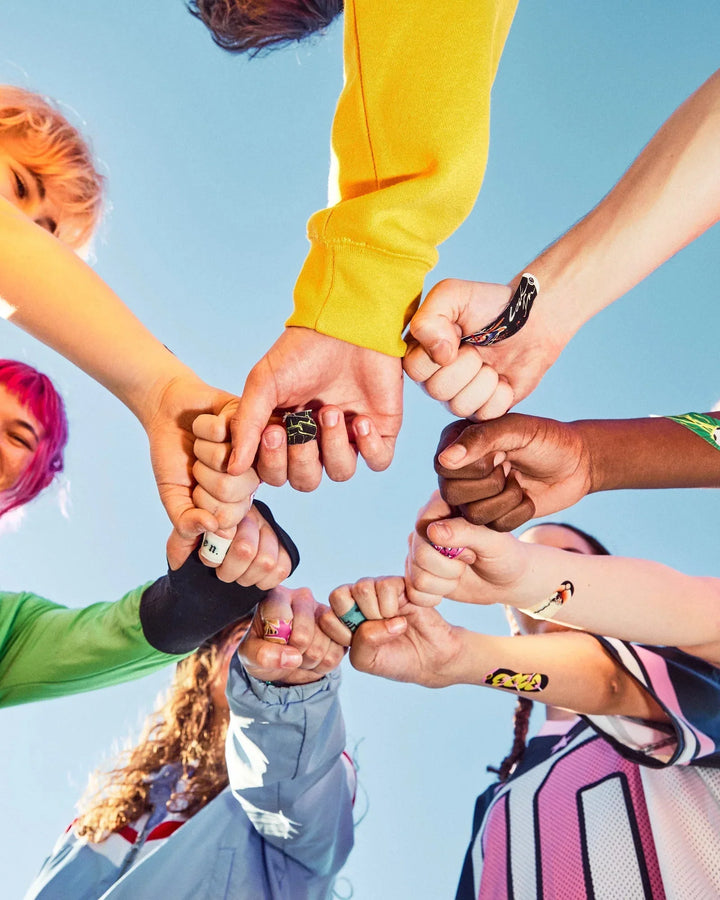Teens with fists together against the sky wearing World of Hurt bandages on knuckles and fingers