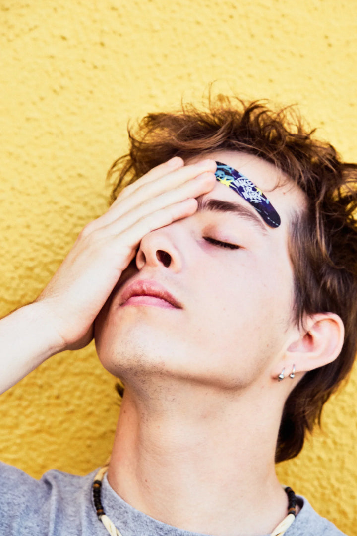 Teen resting against a yellow wall with a World of Hurt bandage above the eye